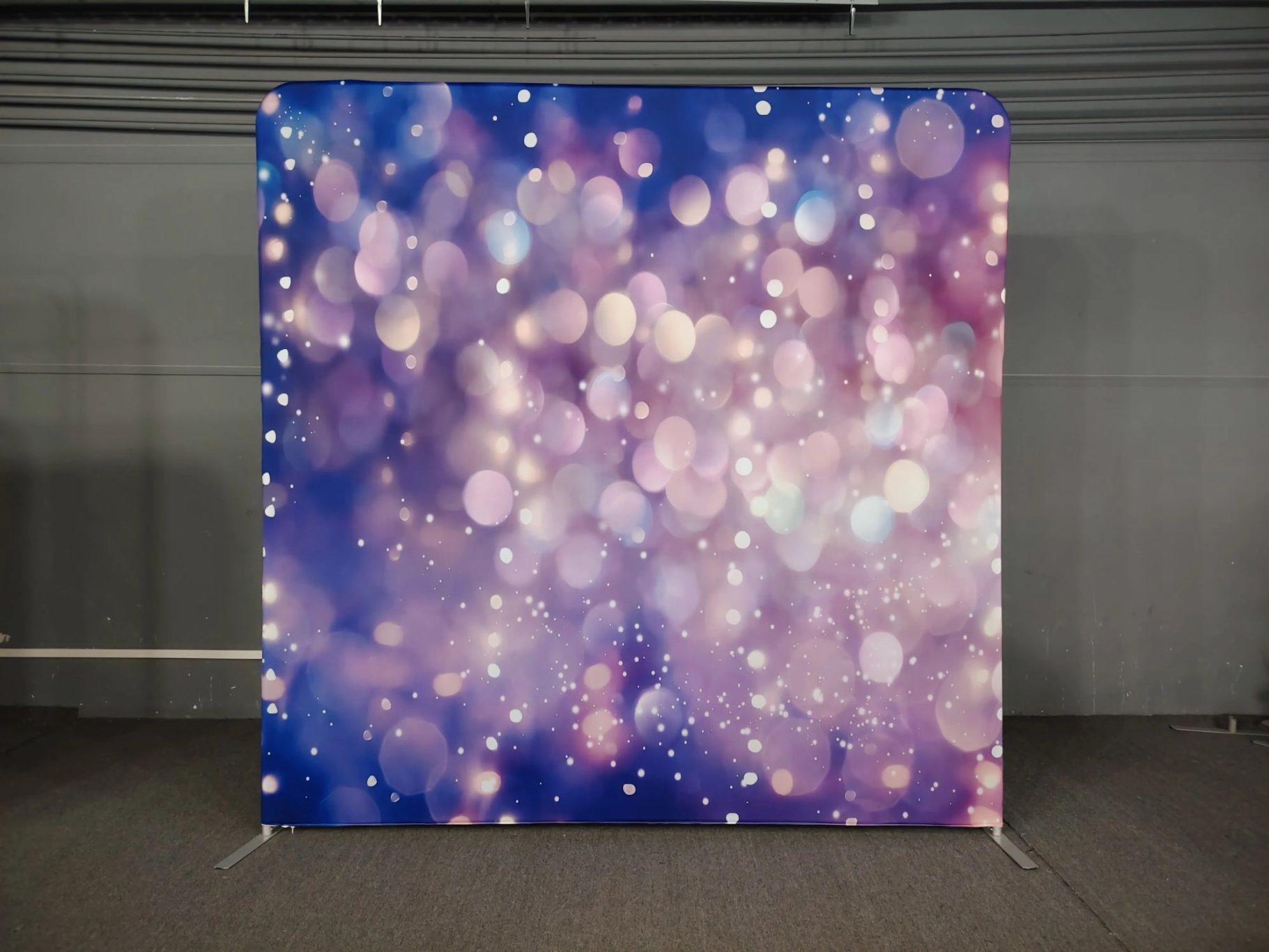 Hintergrund mit verschwommenen lila und rosa Lichtpunkten auf einem einfarbigen Stoff.